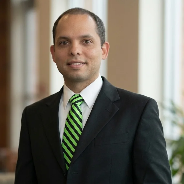 Portrait of Leon Oliver in a dark suit and green striped tie